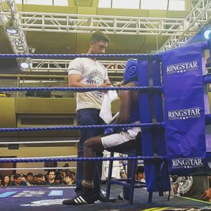 Coach Kumar assisting a boxer during a match.
