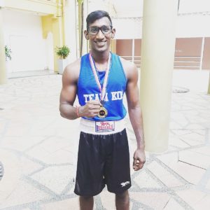 Coach Krishna proudly displaying a medal around his neck.