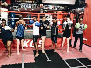 Members of KOS team proudly posing in a row, sporting boxing gloves.