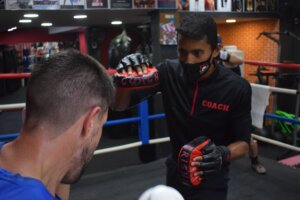 Coach Ravi expertly deflects attacks from enthusiastic trainees during a punching practice session.